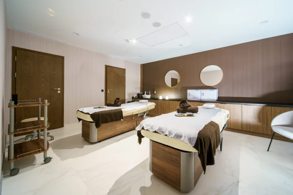 Gabinet masażu w strefie SPA hotelu Biały Kamień: dwa stoły do masażu, drewniana zabudowa i okrągłe lustra