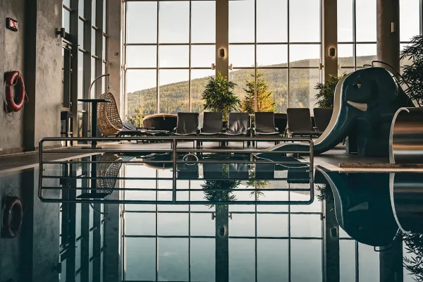 Kryty basen hotelu Biały Kamień z przeszkloną ścianą i widokiem na zalesione zbocze