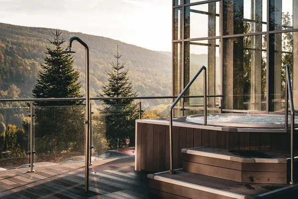 Jacuzzi na drewnianym tarasie hotelu Biały Kamień, w tle świerki i góry